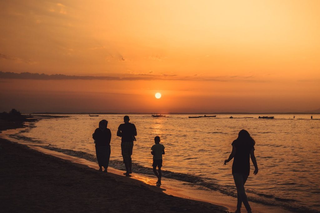 People walking on a beach at the golden hour of sunset.