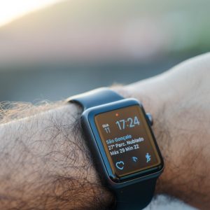 a black smart watch sitting on a fairly hairy mans arm.