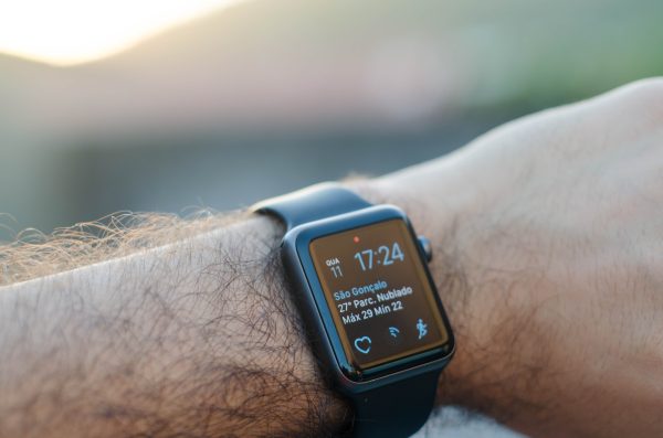 a black smart watch sitting on a fairly hairy mans arm.