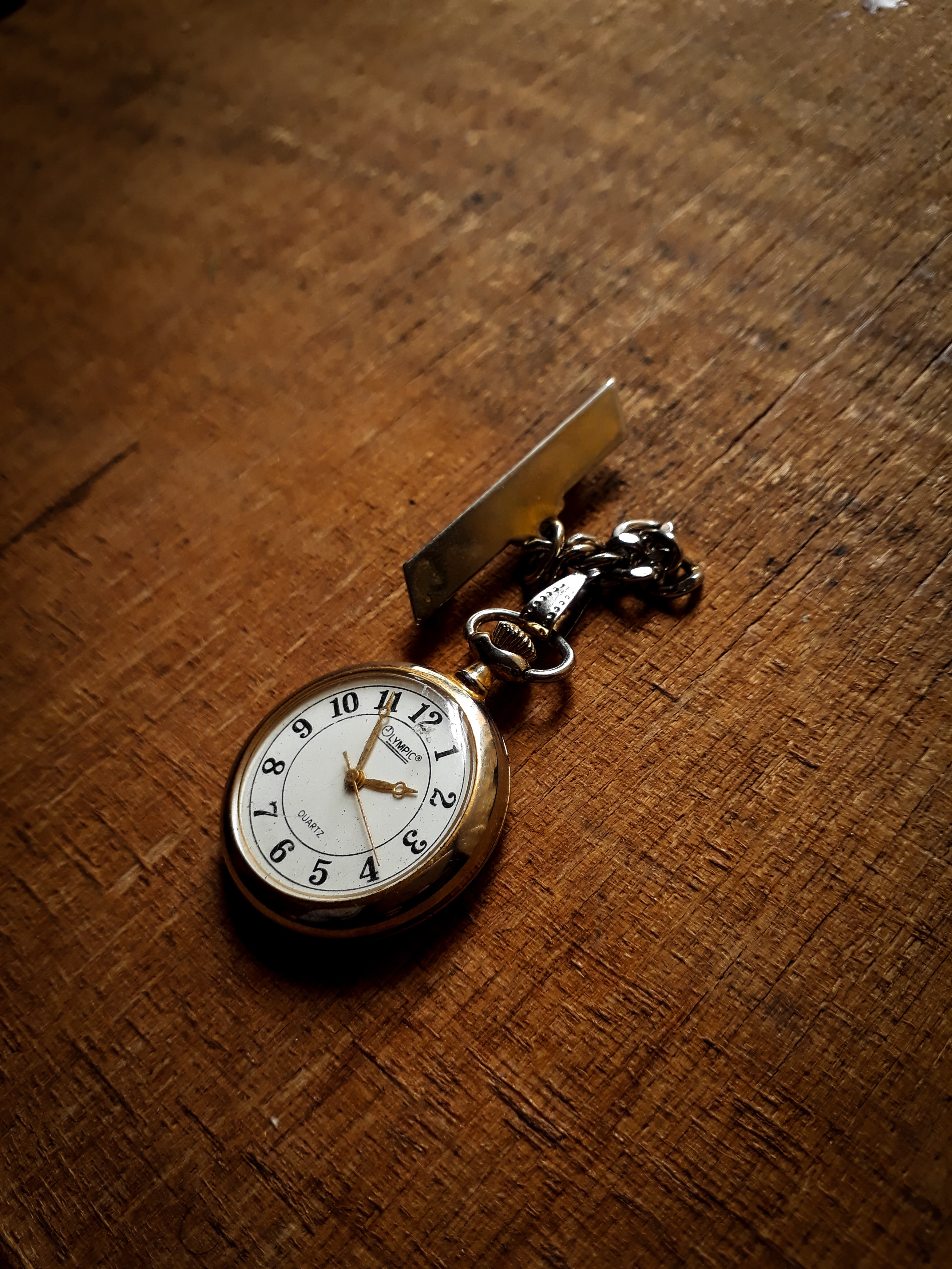 Gold pocket watch with a button hole peg on the end of the chain for fastening to a jacket or pants.