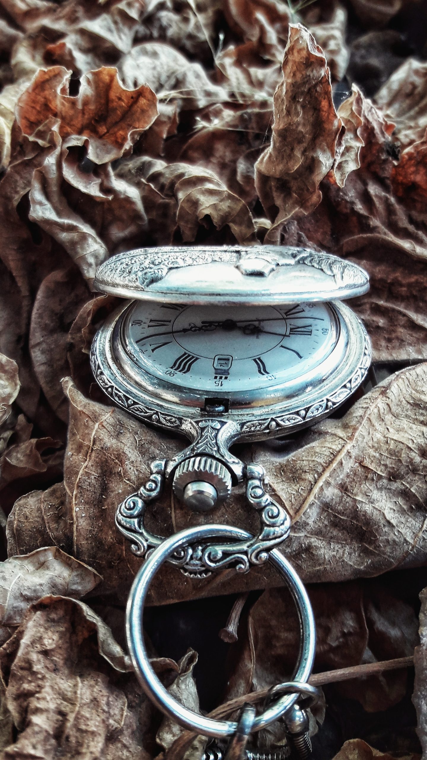 An antique silver watch with faded face details and a seconds keeping subdial sits dramatically against freshly fallen snow.