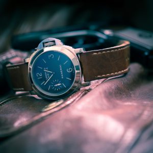Panerai Luminor Marina: 44mm watch with a gold dial and brown leather strap, highlighted by rays of light seemingly coming from inside the watch as a special effect.