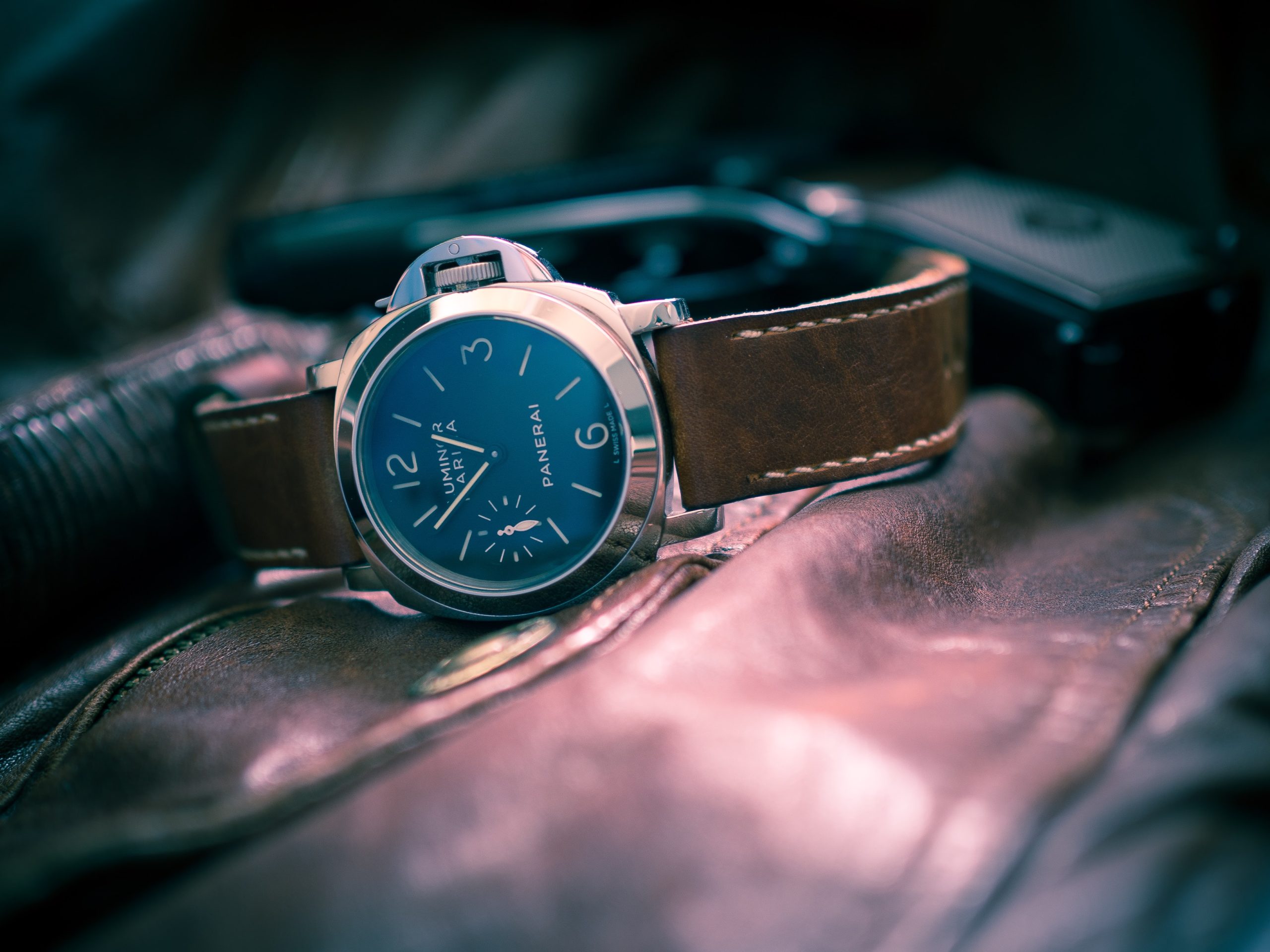 Panerai Luminor Marina: 44mm watch with a gold dial and brown leather strap, highlighted by rays of light seemingly coming from inside the watch as a special effect.