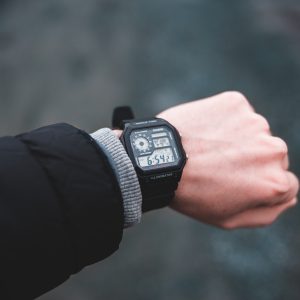 A black square faced digital watch on a mans writst.