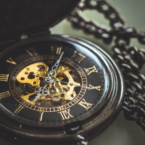 Dark wooden pocket watch with the cover open and a dark brass chain.