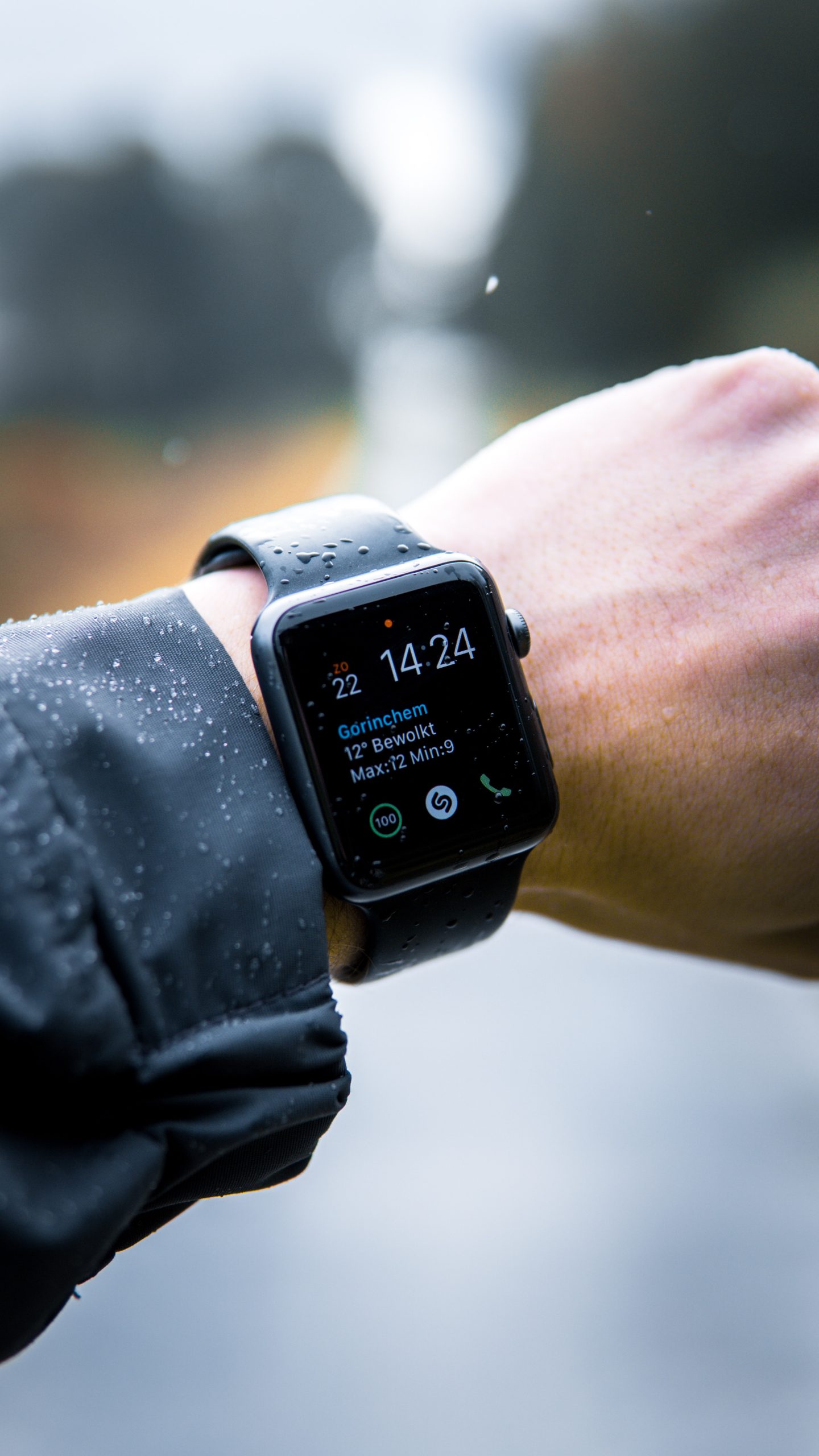 A mans wrist wearing a smart watch with a black band.