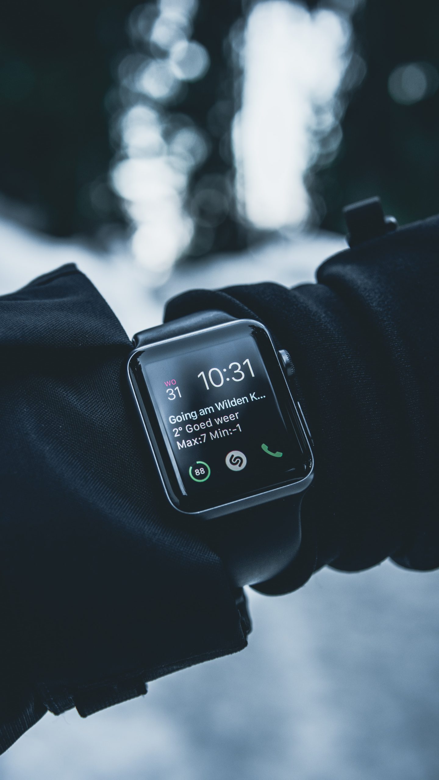 Black cased smart watch with a black band on an arm wearing a black coat in the winter time.