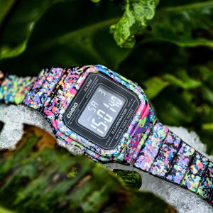 Multi colored paint splotch patterned watch band and face on a digital watch by Casio.